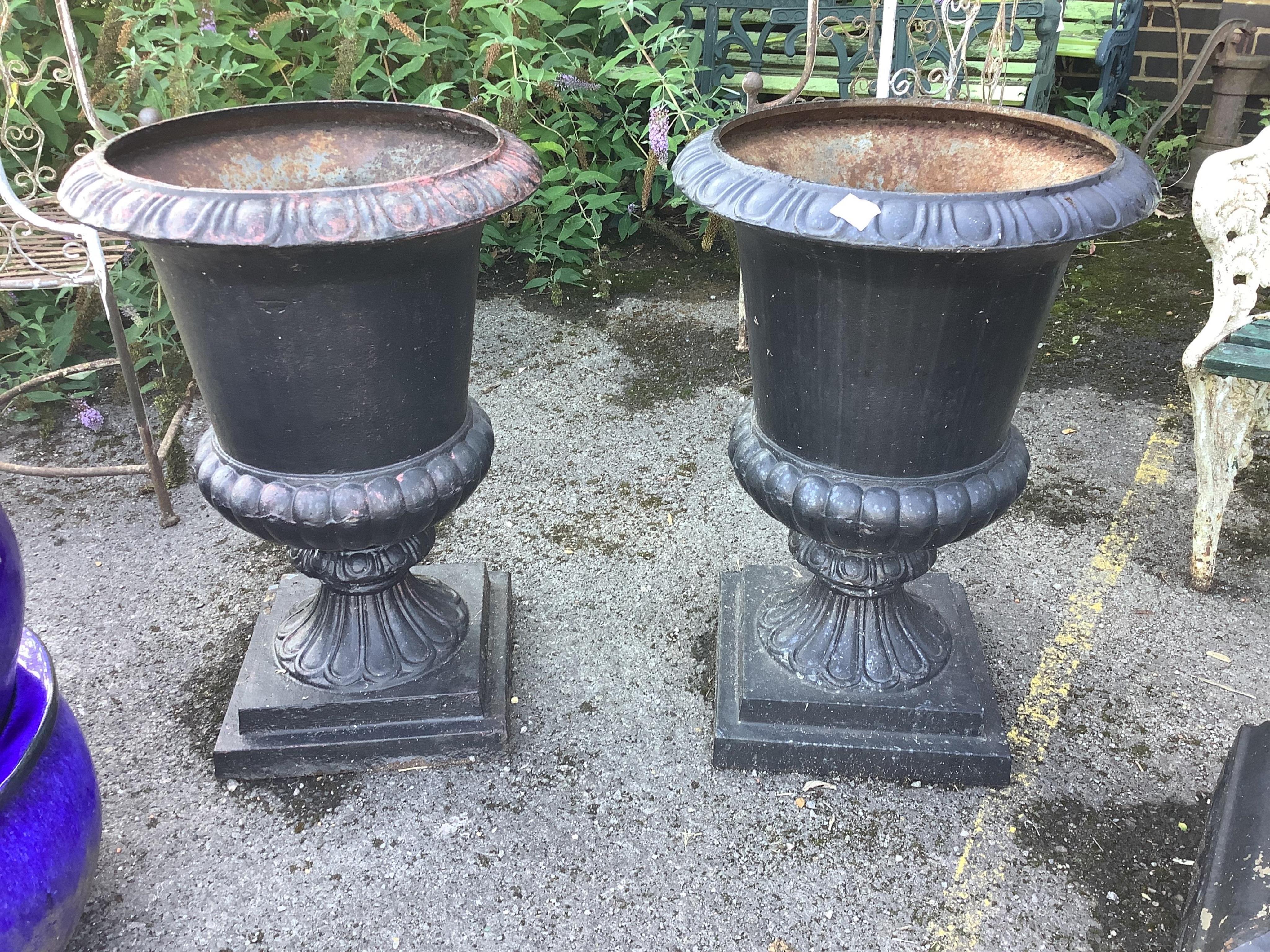 A pair of Victorian style black painted cast iron campana shaped garden urns, on square plinths, diameter 54cm, height 80cm. Condition - fair